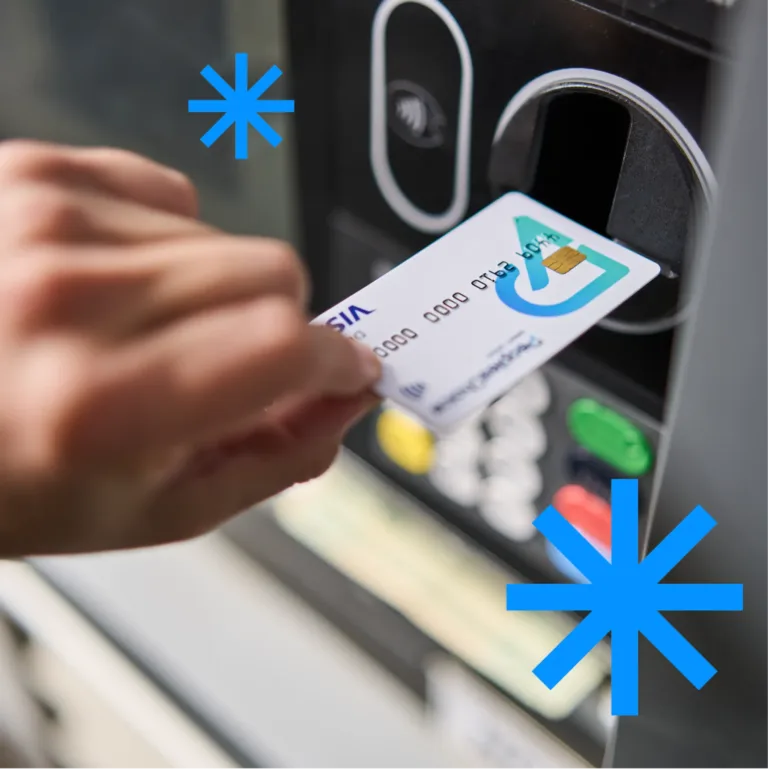 A hand inserting a debit card into an ATM card reader.